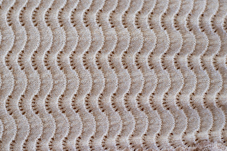 Real beige melange or ombre knitted fabric with ornamental pattern textured background. Detailed warm yarn background.の写真素材