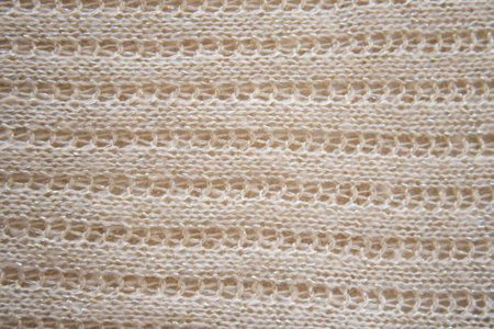 Soft beige knitted fabric as background, closeup. Openwork knitting, horizontal direction. Copy...