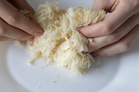 Turkish Traditional Dessert Pismaniye. A woman's hands tear the candy light halvah apart