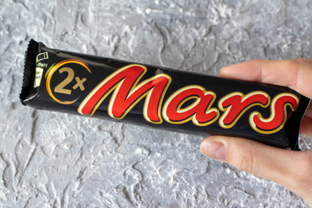 IRPEN, UKRAINE, DECEMBER 2 20222, Mars chocolate bar in the hand of a woman on a gray background,...