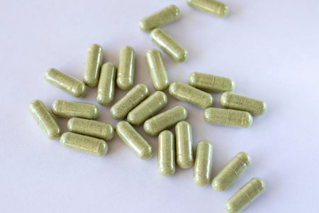Green tablets with herbal vegetables eco powder scattered on a white background.