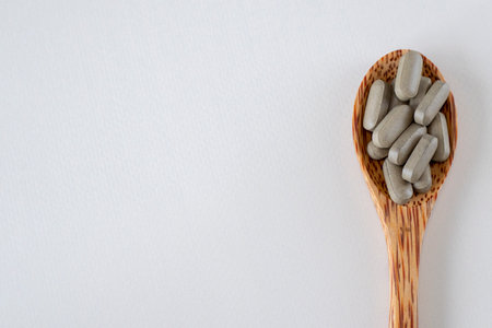 Brown long pills or supplements in a wooden spoon, top view. Copy space for text.の写真素材