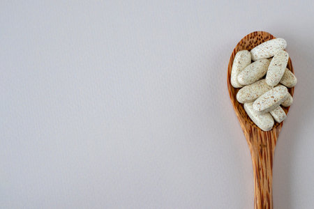 Oval beige stained medicines in a wooden spoon. Lies on the side. Vitamin complex for healthy hair and nails. Design for text. Directly Above View.の写真素材