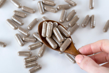 Pau D Arco brown herbal medicine capsules in a wooden spoon in a womans hand. Close-up.の写真素材