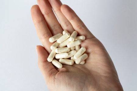 Lots of white capsules in a womans hand. Dietary supplements and medications.の写真素材