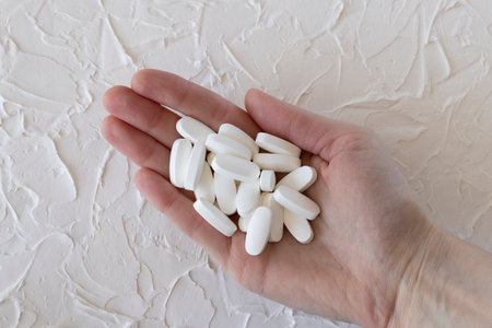 Large white pills, medication or supplements in a womans hand, close-up. Health and wellnessの写真素材