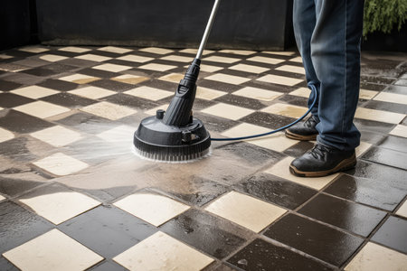 A Man Washes A Street Tile With A High Pressure Washerの素材