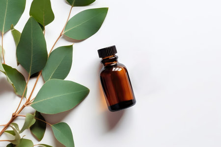Eucalyptus Essential Oil In Small Brown Bottle Next To Eucalyptus On White Background, Top Viewの素材