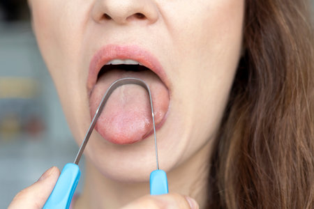 A woman cleans her tongue with a special scraper, close-up.の素材 [FY310209584001]