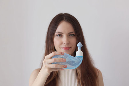A young woman demonstrates the Neti Pot for treating runny nose and colds. Nasal rinsing, irrigation...