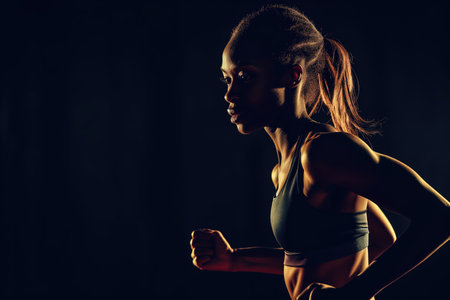 Fit Female Sprinter On Black Background In Sportswear, Radiating Sport Motivation Ample Copy Spaceの素材