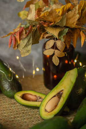 Still life with fresh ripe avocado and autumn leaves on a dark background
