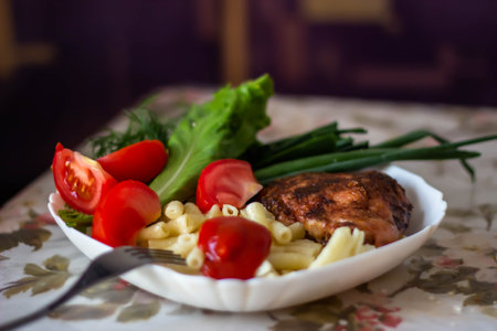 grilled chicken fillet with pasta and vegetables on a white plateの写真素材