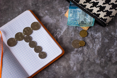 Notebook with coins and banknotes on a marble background. The concept of saving money for the future.の写真素材