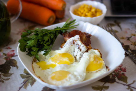 Fried eggs with bacon and vegetables on a plate. Selective focus.の写真素材