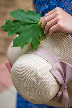Woman wearing a straw hat and holding a green leaf in her handの写真素材