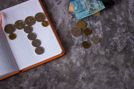 Notepad with coins and money on a gray background. The concept of saving money.の写真素材