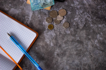 Notebook, coins and pen on a gray background. Business conceptの写真素材
