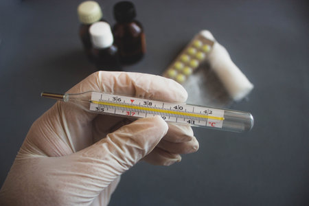 thermometer in a hand in a medical glove on a dark background