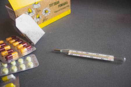 thermometer and pills on a black background with copy space.