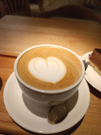 Coffee cup with heart shape latte art on wooden tableの写真素材