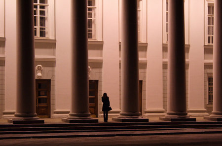 girl - student at the entrance in university between pillars wait the carの写真素材