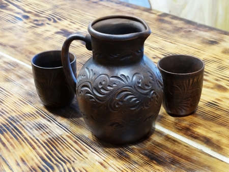 Ceramic jug with glasses on a wooden table. Ceramic set for wine, kvass or compote.の写真素材