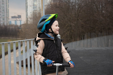 a little boy on a scooter in a protective helmet.Popular protect equipments for safety kids on street of city.の写真素材