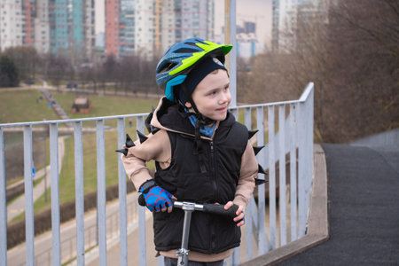 a little boy on a scooter in a protective helmet.Popular protect equipments for safety kids on street of city.の写真素材