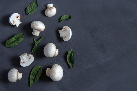 Fresh champignons with basil leaves on a black backgroundの写真素材