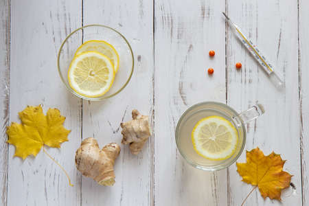 Ginger tea with lemon leaves and a thermometer on a white tableの写真素材