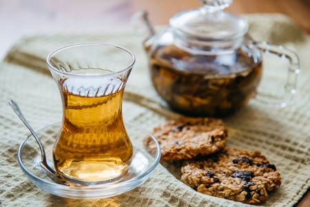 Herbal tea in a glass cup with cereal cookies and a teapot stand on a wooden table.の写真素材