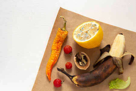 Ugly food. Spoiled products lie on brown paper on a white background. Horizontal orientation, top view.の写真素材