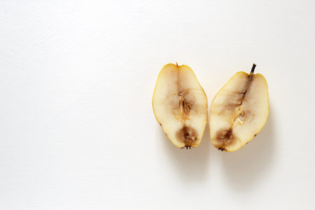 Ugly food. Two halves of a spoiled old yellow pear on a white background. Horizontal orientation, top view.の写真素材