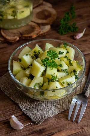 Pickled zucchini with herbs in a transparent bowl on a wooden background. Fermented vegetables. Vertical orientationの写真素材