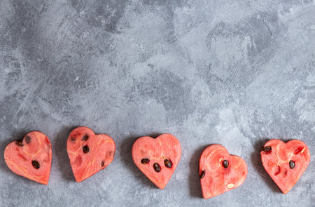 Watermelon hearts bottom in a row on a gray concrete background. Top view, copy space.の写真素材