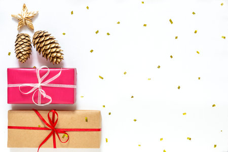 Christmas gift boxes with golden cones, star on a white background with gold sparkles. New Year Card...