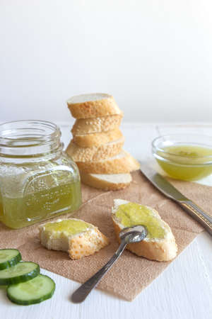 Breakfast with a white baguette and green cucumber jam on a white background. Vertical orientation, place for text.の写真素材