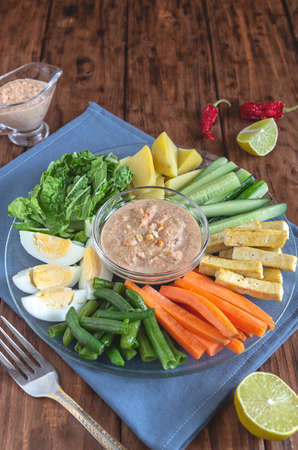 Gado gado vegetable salad with eggs and tofu on a wooden table.の写真素材