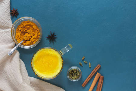Indian drink golden milk with turmeric and spices on a blue background. Top view, place for text.の写真素材