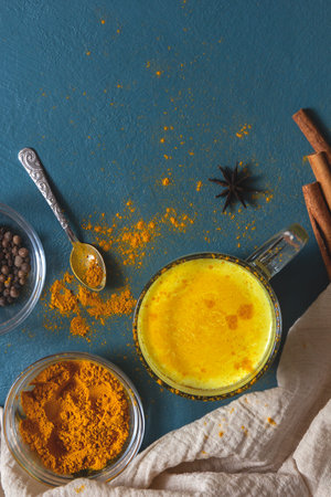 Indian drink golden milk with turmeric and spices on a blue background. Top view, place for text.の写真素材