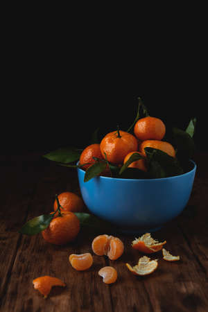 Cherry tangerines in a bowl on a wooden table. Vertical photo in low key with place for text.の写真素材