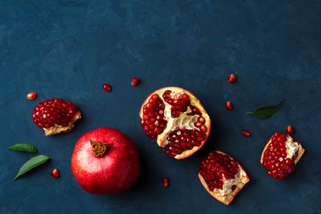 Flat lay with fresh pomegranate on a dark blue background. Top view, copy space