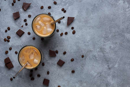 Iced coffee in a glass cup with a metal straw on a gray concreteの写真素材