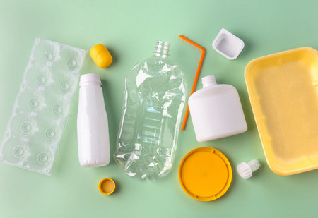 Recycled materials from different plastic on a green background. Zero waste concept. View from above