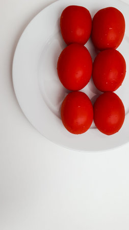 Six red ripe, juicy, wet, mouth-watering, healthy tomatoes on a white round porcelain plate. Place...