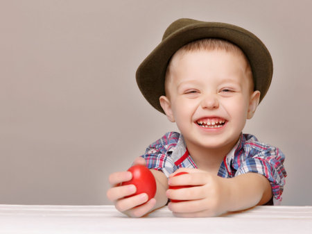 Laughing little boy 4 years old. He looks at the viewer. In the hands it has two red Easter eggs.