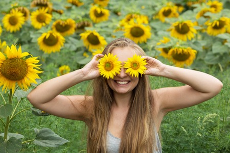 The girl with blond hair covers the face and eyes with flowers oの写真素材