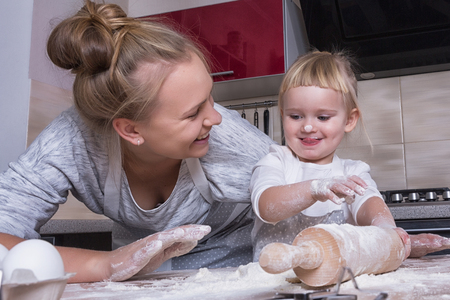 Happy family! A tiny daughter spends time with her mother in the kitchen to bake cookies. Mother's Day.の写真素材