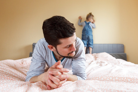 Father and daughter. Dad argued with his daughter, he punished her. He lays and thinks what can be done. Blur and selective focus.の写真素材